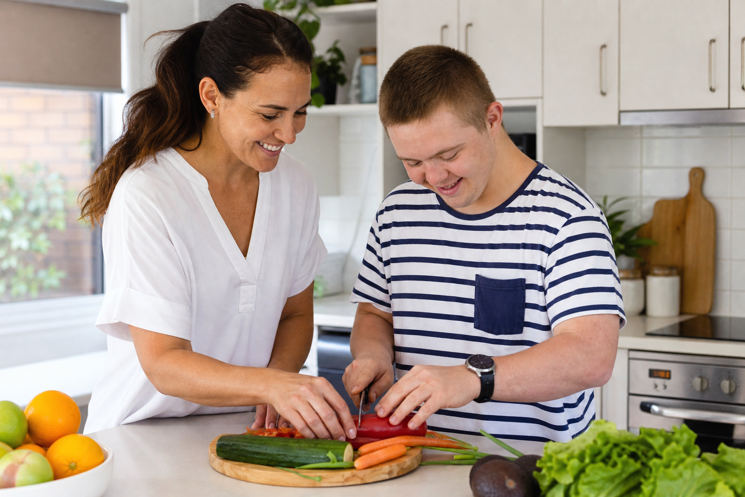 A caregiver and participant preparing food in a bright kitchen